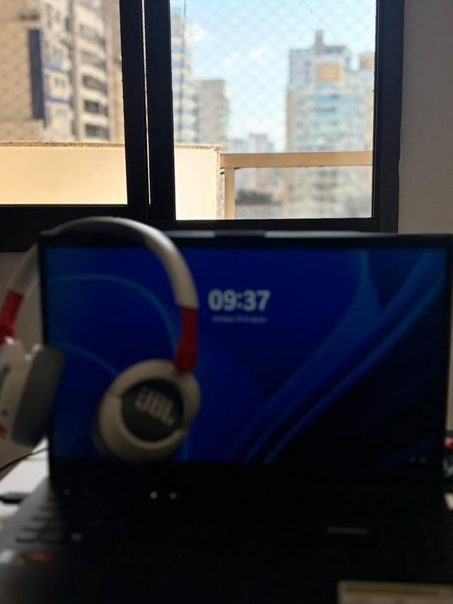 Notebook aberto em frente à janela, com vista para os prédios de Vila Velha